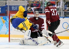 SOCHI, RUSSIA - FEBRUARY 15: Sweden's Daniel Sedin #22 goes airborne as Latvia's Arturs Kulda #32 trips him in front of the net as Kristers Gudlevskis #50 defends during men's preliminary round action at the Sochi 2014 Olympic Winter Games. (Photo by Andre Ringuette/HHOF-IIHF Images)